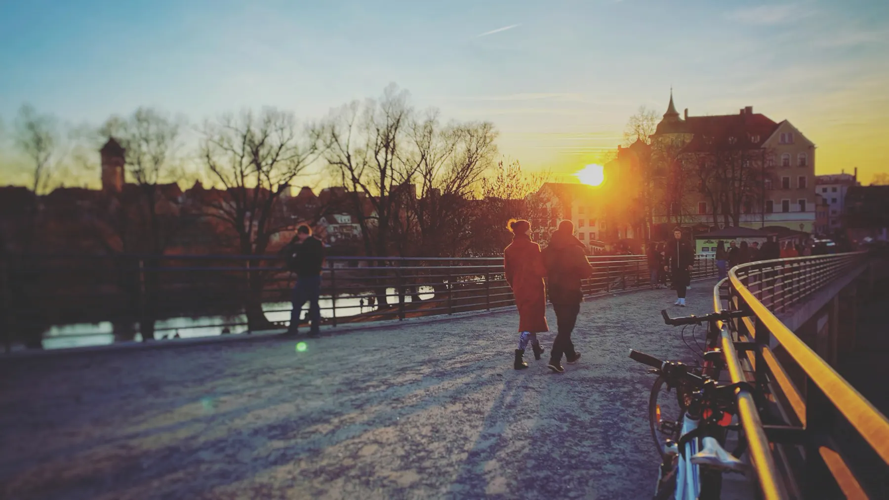 Menschen auf der Steinernen Brücke in Regensburg bei Sonnenuntergang