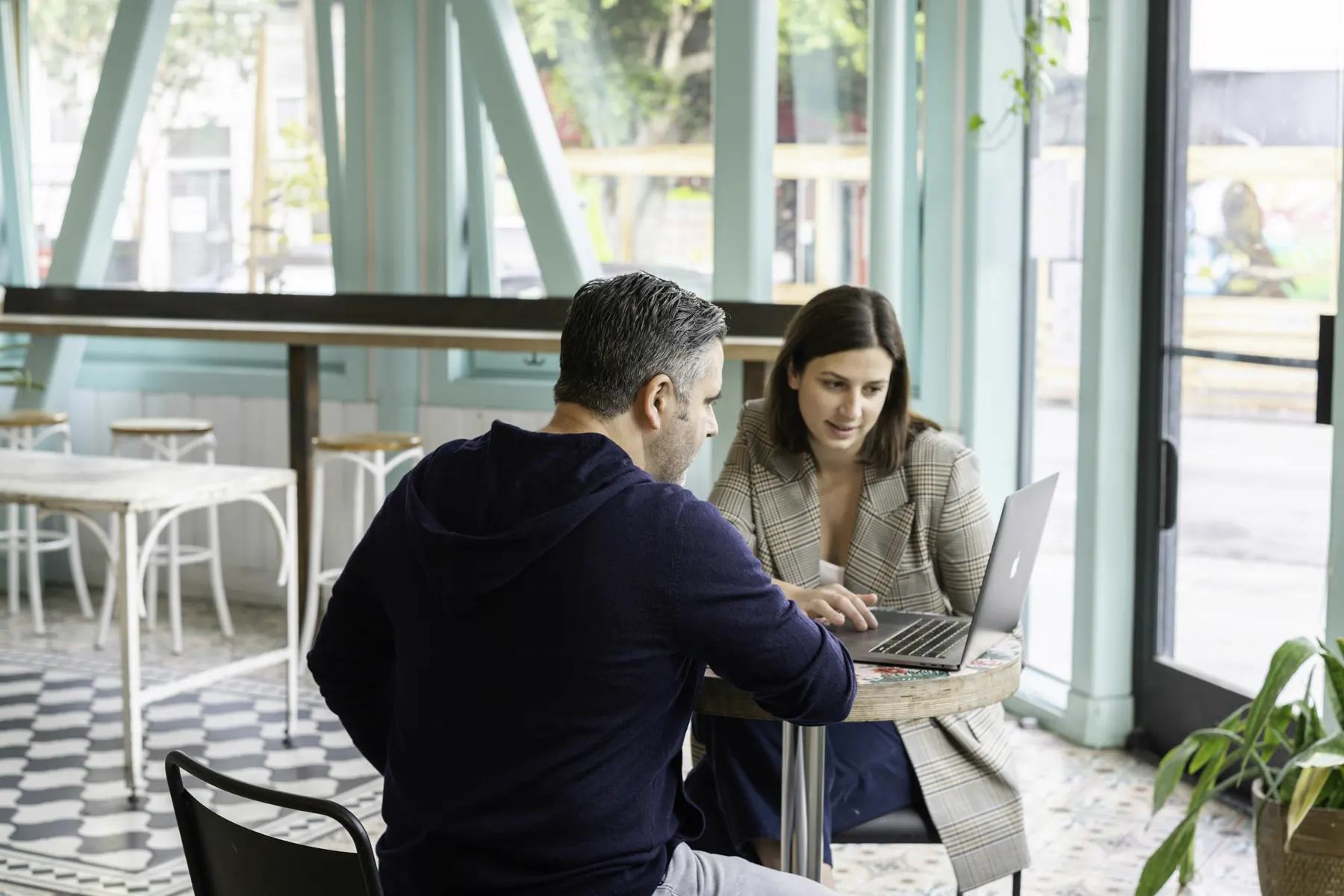 Zwei Personen besprechen am Café-Tisch etwas am Laptop